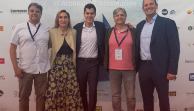 Five adults pose for a photo in front of a conference banner that reads 'Conocimiento, Visión, Futuro' with sponsor logos visible behind them.