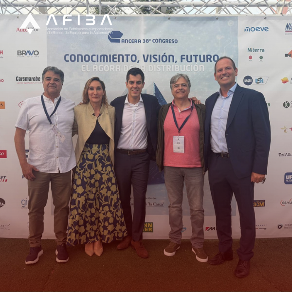 Five adults pose for a photo in front of a conference banner that reads 'Conocimiento, Visión, Futuro' with sponsor logos visible behind them.