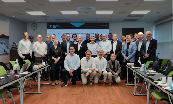 Group of about 30 professionals in business attire posing for a group photo in a conference room, with a presentation screen and two logos at the top (AFIBA and EGEA).
