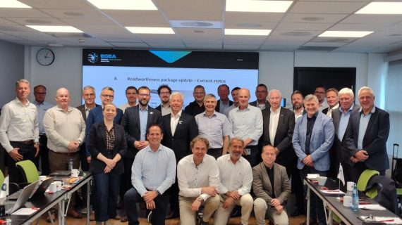 Group of business professionals posing for a photo in a conference room with a large screen behind them.