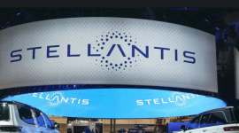Large curved banner with the STELLANTIS logo floats above a booth at a car show, with two vehicles on display beneath it.